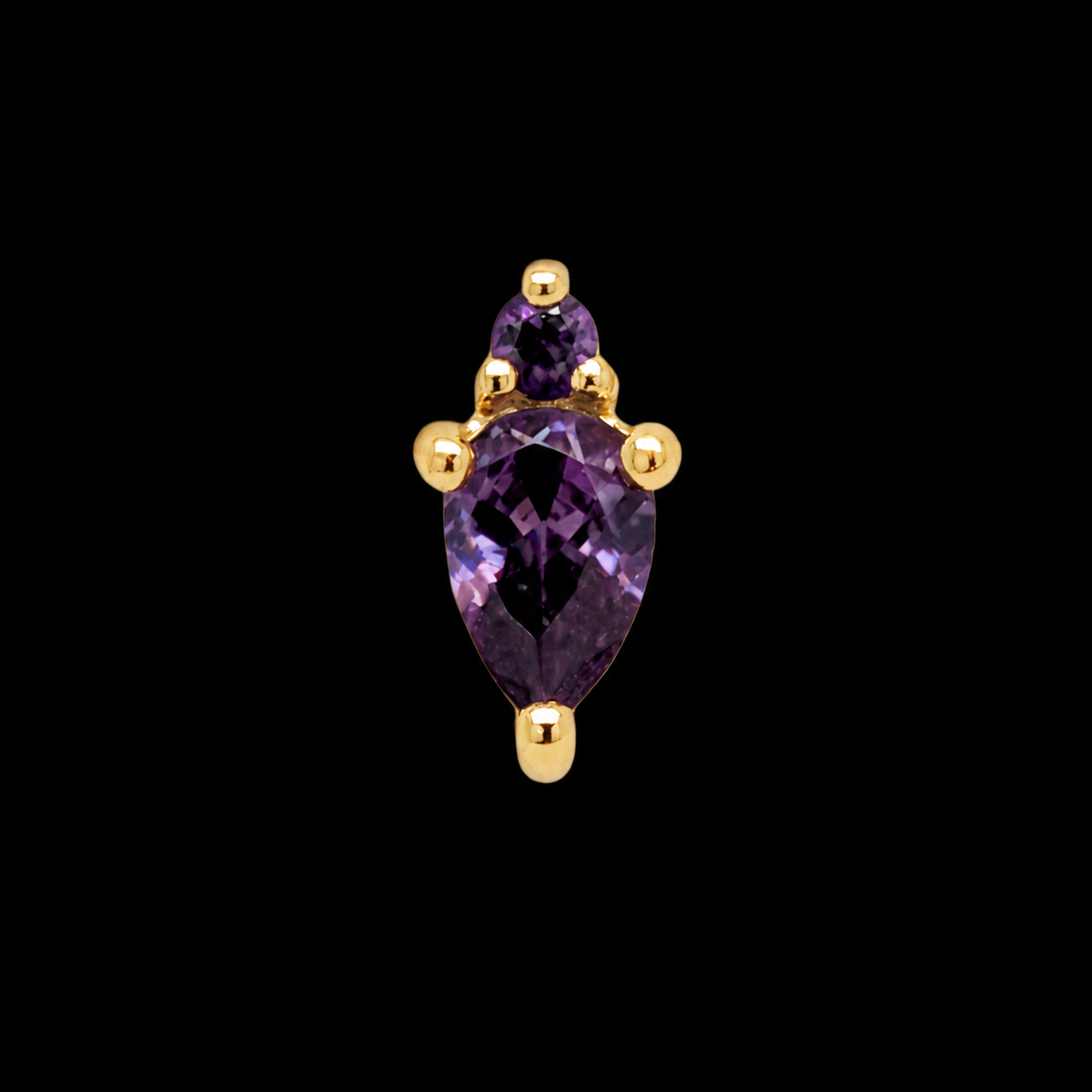 A pear-cut violet amethyst with a small round stone above it, set in gold claws, on black.