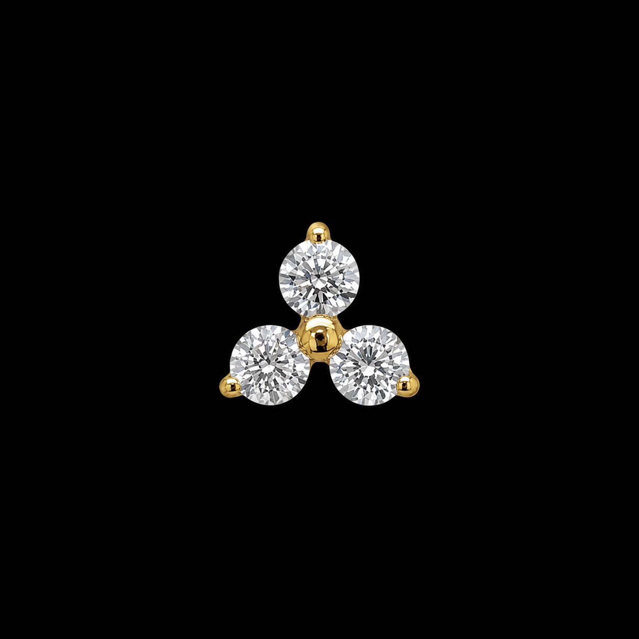Three round white stones set in a trefoil in gold claws, photographed on black.