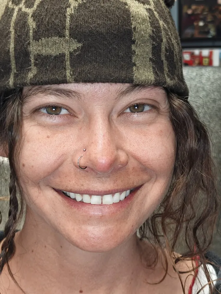 Healed nostril piercing with a fine ring, on a smiling client